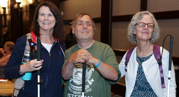 Three NFB of Connecticut members smile together.